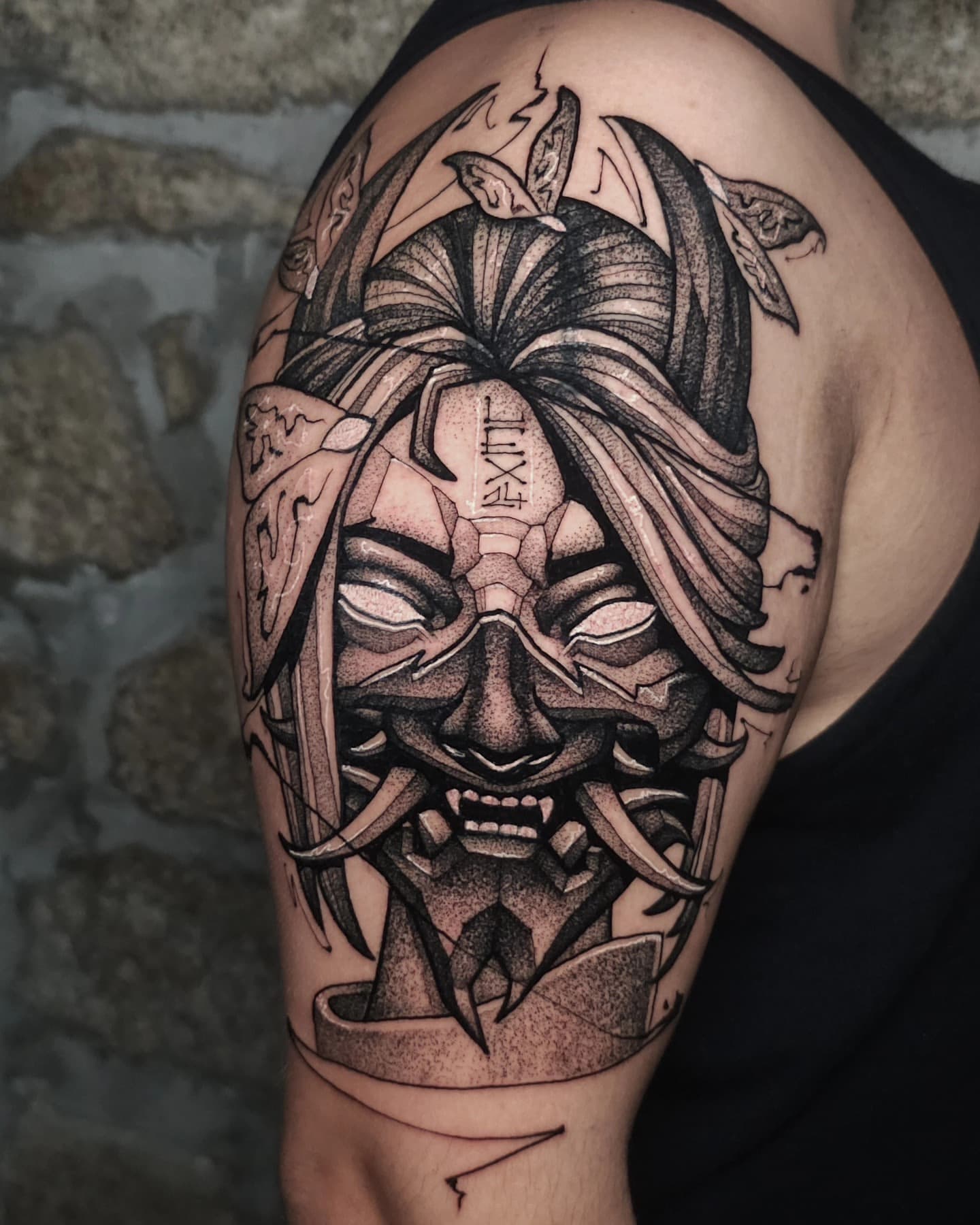 Oni demon mask blackwork tattoo on upper arm by Lex Almeida, Porto